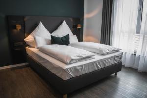 菲尔德施塔特Hayta Hotel Stuttgart Airport Messe的一张带白色床单和枕头的床