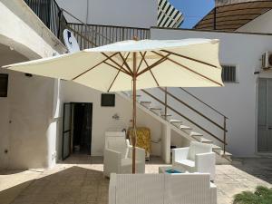 圣凯撒利亚温泉Villa Azzurra Sct的一把大伞,坐在椅子和楼梯旁