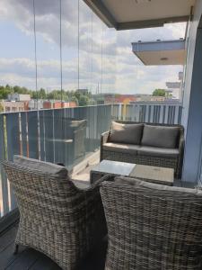 格但斯克Apartament North Coast - nad morzem的阳台配有两把椅子、一张桌子和一张沙发