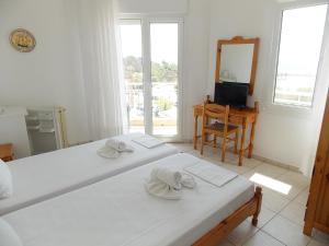利迈纳里亚Hotel Sgouridis的一间白色卧室,配有两张床和镜子