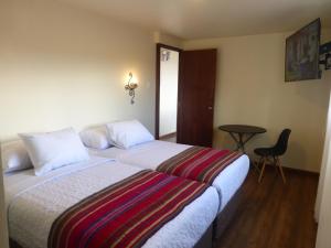 库斯科Casa Durand的酒店客房配有一张床铺和一张桌子。