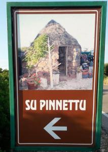奥罗塞伊Su Pinnetu的箭头在石头建筑前的标志