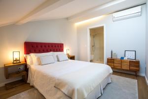 波瓦-迪瓦尔津Lofts - Casa do Metro的一间卧室配有一张白色大床和红色床头板