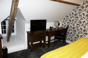 North Elmham国王头像酒店的一间卧室配有一张桌子、一台电视和一张床