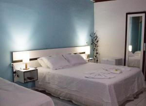 佩尼多Pousada Doce Mel的卧室配有一张白色大床和镜子