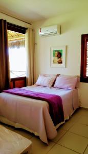 弗雷谢拉斯Bangalô Eco Residence Flecheiras的一间卧室配有一张带紫色床单的床和窗户。