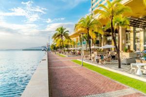 西班牙港特立尼达凯悦酒店的一条旁的海滨步道,上面有棕榈树和一座建筑