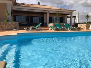 塞图巴尔卡萨尔达斯奥烈日尔拉斯宾馆的一个带椅子的游泳池以及一座房子