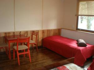 卡布里Rannakodu的一间卧室配有红色的床和一张桌子及椅子