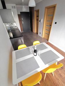 奥斯威辛Apartament Cyprys 2的厨房配有白色的桌子和黄色的椅子