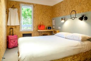塞克兰Hôtel Moustache Lille - Seclin的卧室配有白色的床和粉红色的行李箱
