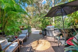 TinbeerwahNoosa Hinterland Retreat的庭院配有桌椅和遮阳伞。