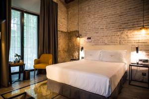 塞维利亚Hotel Legado Alcazar的卧室配有白色的床和砖墙