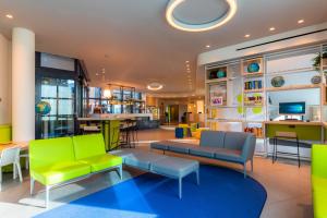 巴格那提卡贝加莫机场酒店的大堂设有绿色和蓝色的家具,酒吧