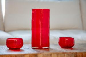 贝圣安那渔村酒店的红色花瓶坐在桌子上,有两个杯子