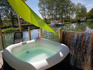 圣让德洛讷Cottage flottant Saint Jean de Losne option jacuzzi的浴缸位于河边的甲板上