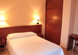 拉科鲁尼亚麦卡酒店的卧室配有白色的床和木制床头板