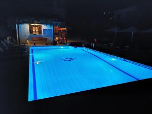 卡拉内拉Pagaseon Rooms and Apartments的夜间游泳池,灯光蓝色