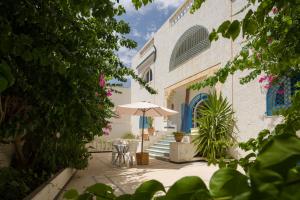 哈马马特腓尼基别墅酒店的一座带遮阳伞和椅子的庭院和一座建筑