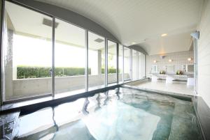淡路托托海风淡路酒店的一座大型游泳池,设有玻璃窗户,位于大楼内