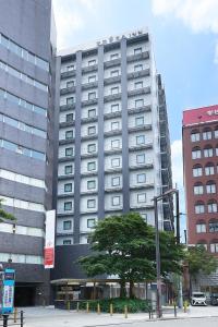 大阪Sotetsu Fresa Inn Osaka Namba的前面有一棵树的高楼