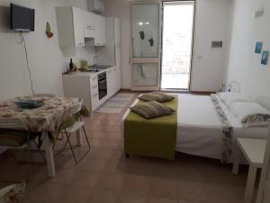 圣卡特琳娜迪纳德Monolocale Santa Caterina的一间卧室配有一张床铺和一张桌子,还设有一间厨房
