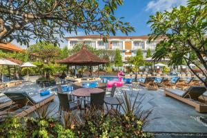 库塔Kuta Beach Club Hotel的一个带桌椅的游泳池的度假酒店