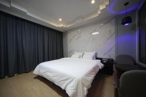 釜山Bestie Hotel的卧室配有白色的床和紫色灯