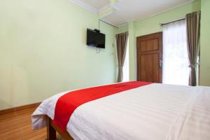 泗水RedDoorz near Juanda International Airport的卧室配有红色和白色的床和电视。