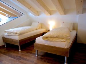 贝特默阿尔卑Bergquelle Dachwohnung的阁楼间设有两张单人床和窗户