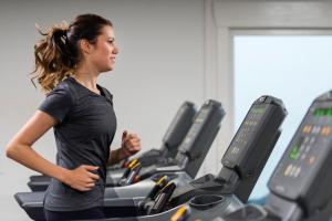 巴勒纳绍布鲁尔斯运动酒店的一名在健身房跑步机上跑步的女人