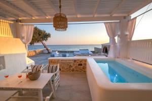 维查德Aegean Melody Suites & Villas的一个带桌椅的室外游泳池以及大海