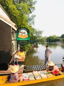 佛丕Baan Bon Resort Bang Tabun的一群人乘着一条河上的小船