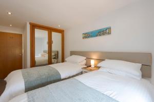 纽基The Beach House & Porth Sands Apartments的一间卧室配有两张床和镜子