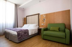 罗马吉奥里纳森纳勒酒店的一间卧室配有一张床和一把绿色椅子
