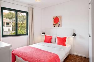 丰沙尔Luxury View Apartment Funchal的一间卧室配有一张带红色枕头的床和一扇窗户