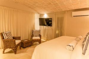卡塔赫纳Casa La Merced by Mustique的配有一张床和一把椅子的酒店客房