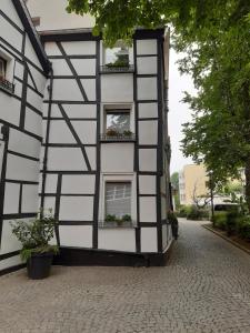 埃森Historisch übernachten Brinkerplatz 3的黑白的建筑,有窗户和盆栽植物