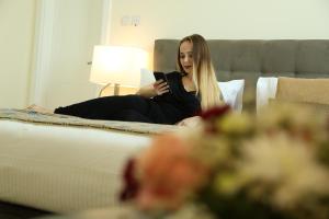 富查伊拉Uptown Hotel Apartment Fujairah By Gewan的坐在床上看着手机的女人