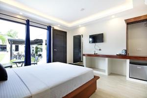 邦劳OHANA, Panglao Resort.的一间卧室设有一张床、一台电视和一个阳台。
