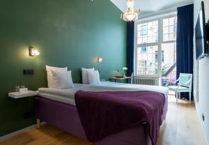 斯德哥尔摩玻璃屋赫尔斯登酒店的一间卧室配有一张大床和紫色毯子