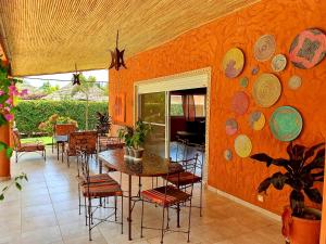 萨利波图尔Safari Village Saly的用餐室设有橙色墙壁,配有桌椅