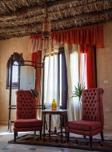 Al Qaşr森达沙漠度假酒店的带窗户的客房内配有两把椅子和一张桌子