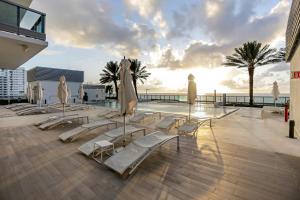 迈阿密海滩迈阿密假期蒙特卡洛公寓的一组躺椅和遮阳伞,位于游泳池旁