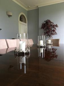 兰代洛Llwynhelig Manor的一间设有一张玻璃桌的房间,上面有蜡烛