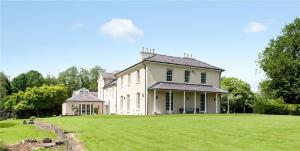 兰代洛Llwynhelig Manor的一座大型白色房子,设有大片草地