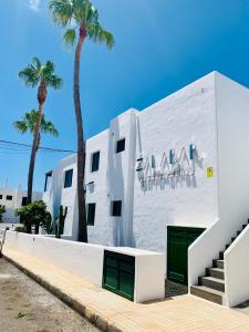 蒂亚斯Apartamentos Zalabar的两棵棕榈树的白色建筑
