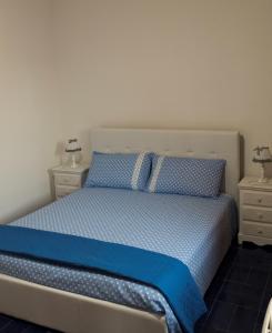 托里德欧索B&B Il Villino的一间卧室配有一张带蓝色床单的床和2个床头柜。