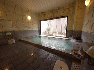 山梨市路线居山梨酒店的一间带游泳池及窗户的浴室