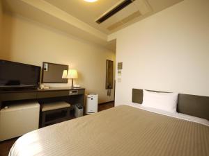 山梨市路线居山梨酒店的一间卧室配有一张床、一张书桌和一台电视